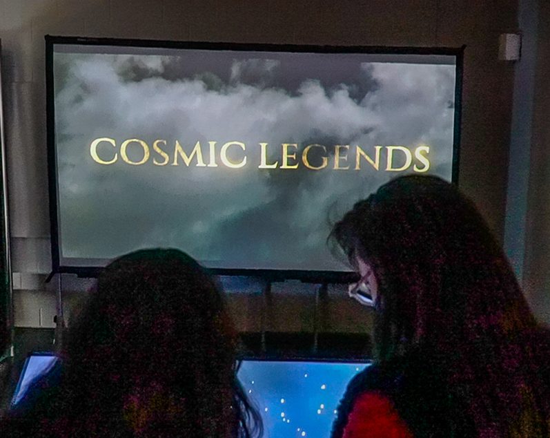 Visitors in front of the Cosmic Legends title screen