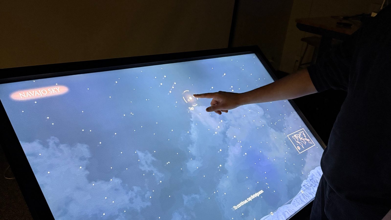 A visitor's hand reaching for the glowing Betelgeuse star on the Navajo sky